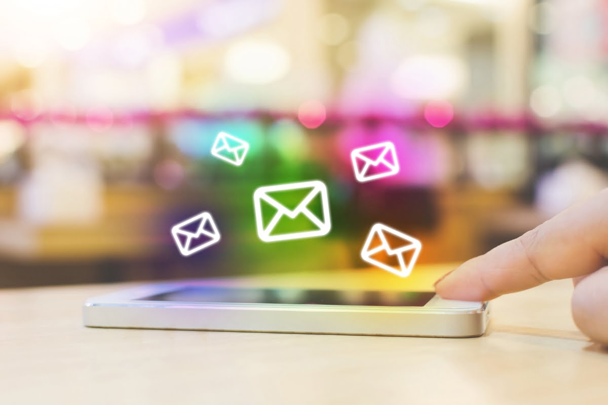 A hand is pointing at an email icon on a smartphone, emphasizing the importance of email marketing in the spa industry.