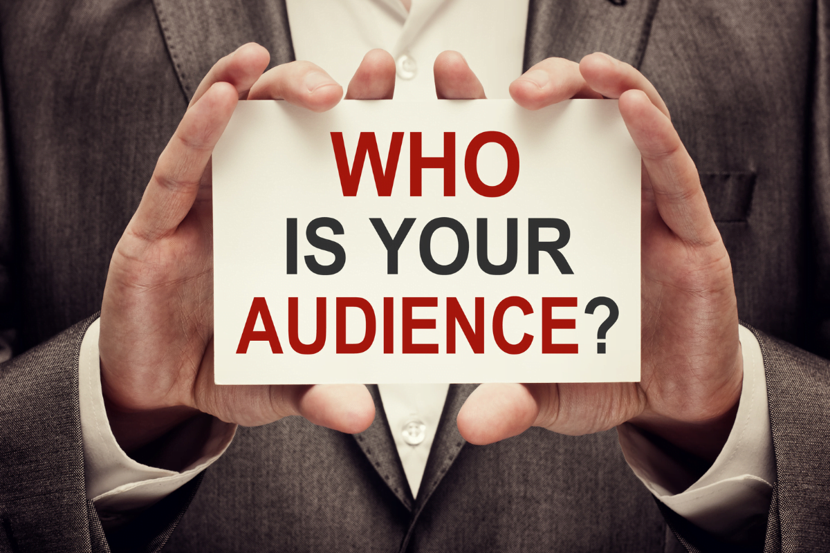 A man's hands holding a piece of paper that says, "Who is your audience?"