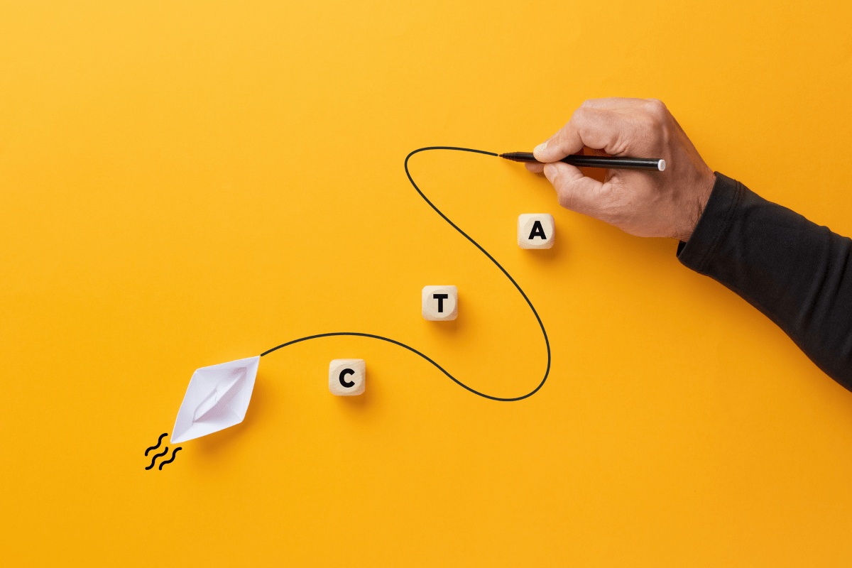 A man is creating a paper boat on a yellow background with the letters CTA for call-to-action.