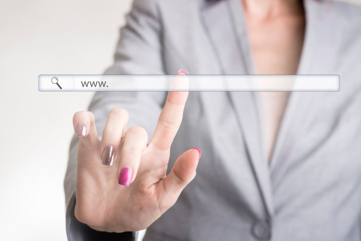 A business woman's hand is pointing at a search bar while conducting a website audit.