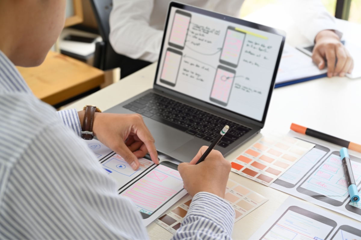 A group of people collaborating on a laptop at a desk, brainstorming simple website design ideas for beginners.