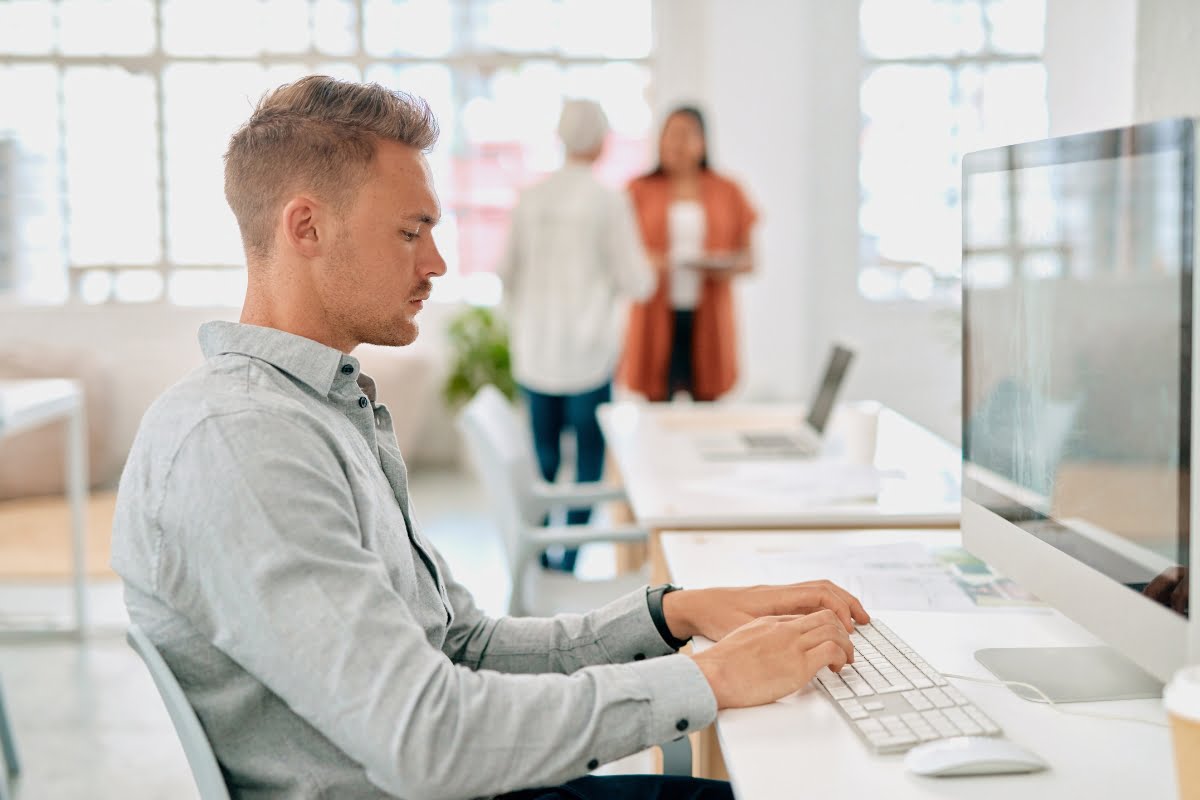 A man working on a computer in an office, diligently updating a website.