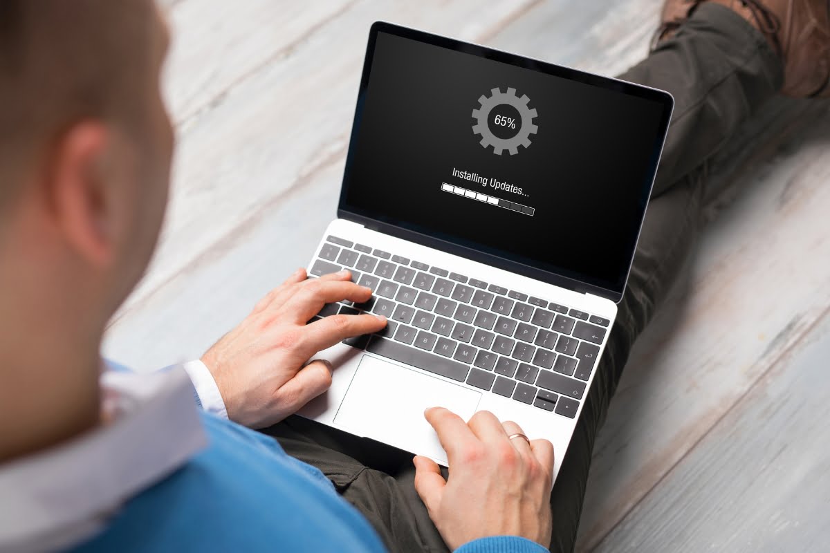 A man is using a laptop with gears on it to work on updating a website.