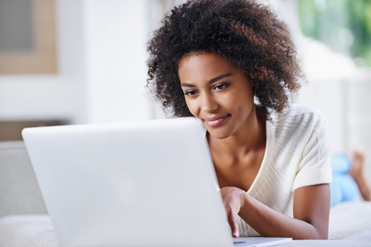 A young woman, diligently using a laptop at home, updates her website.