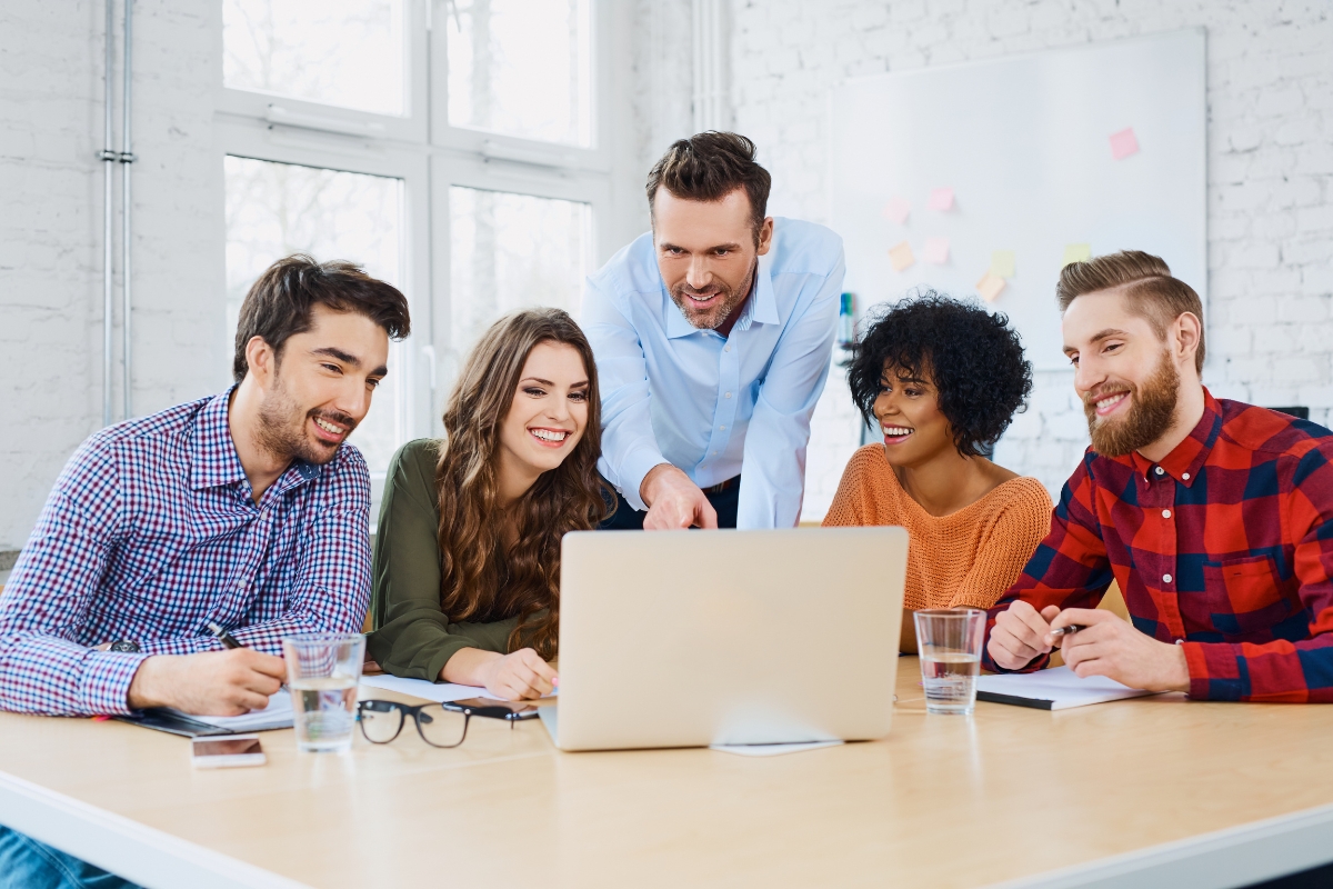 A group of people sitting around a table looking at the best local seo company on a laptop.