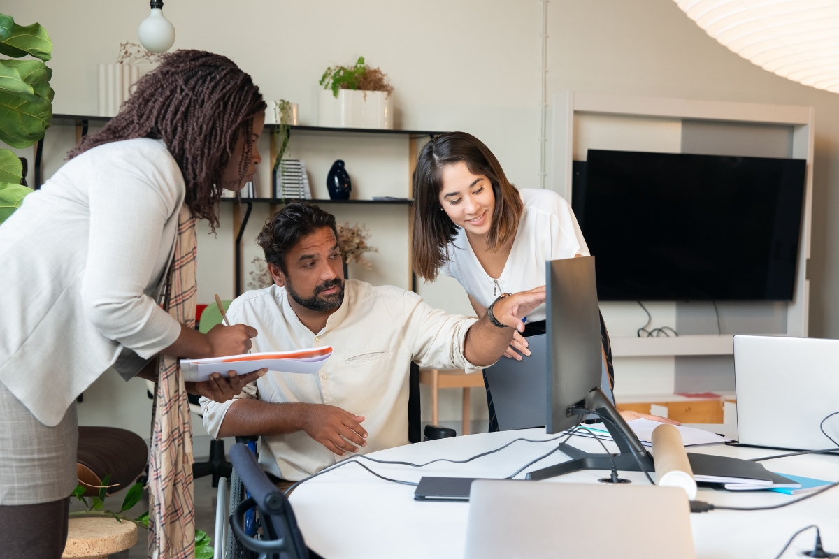 Three people in an office looking at a computer screen to choose the best local SEO company.