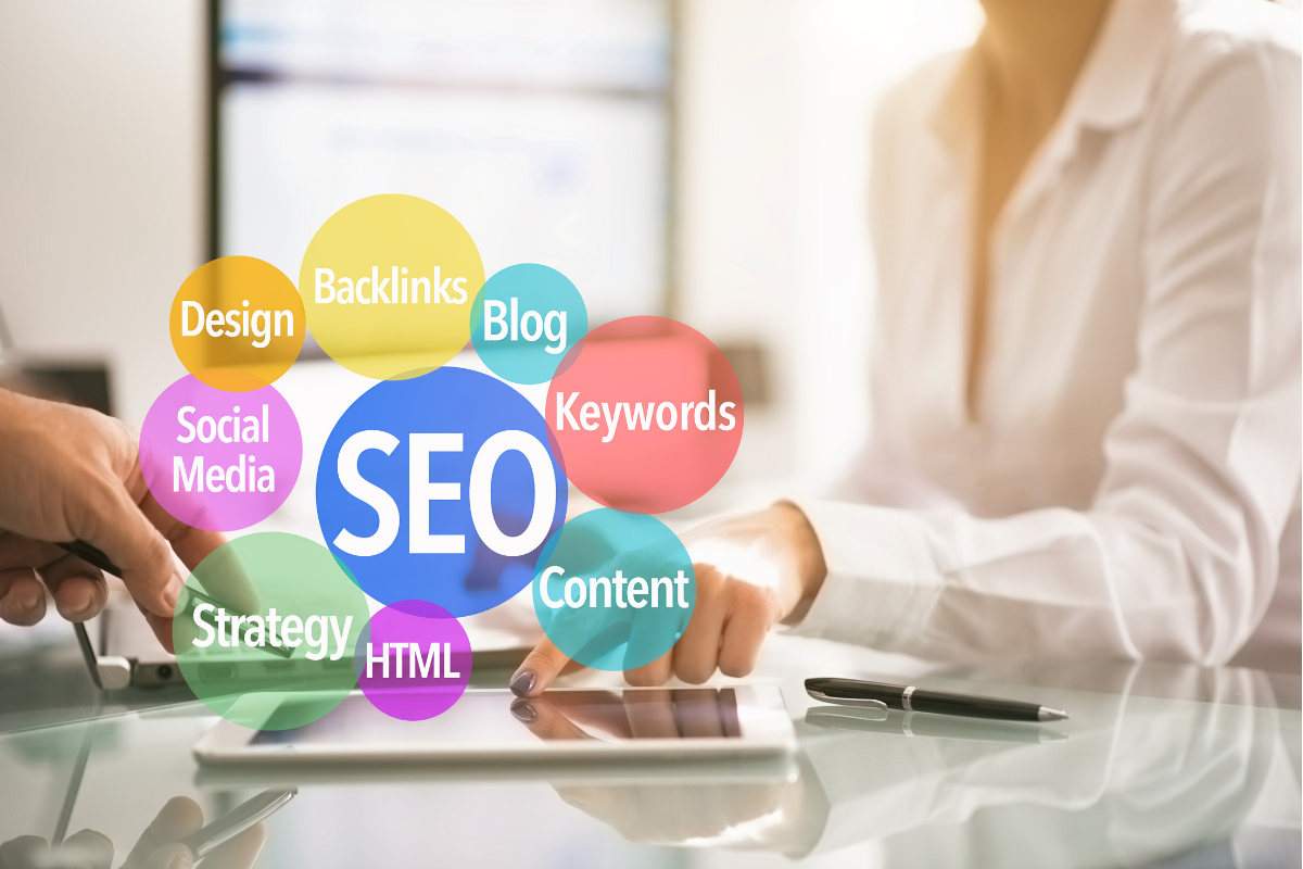 A woman working on a laptop on her desk with the word SEO.