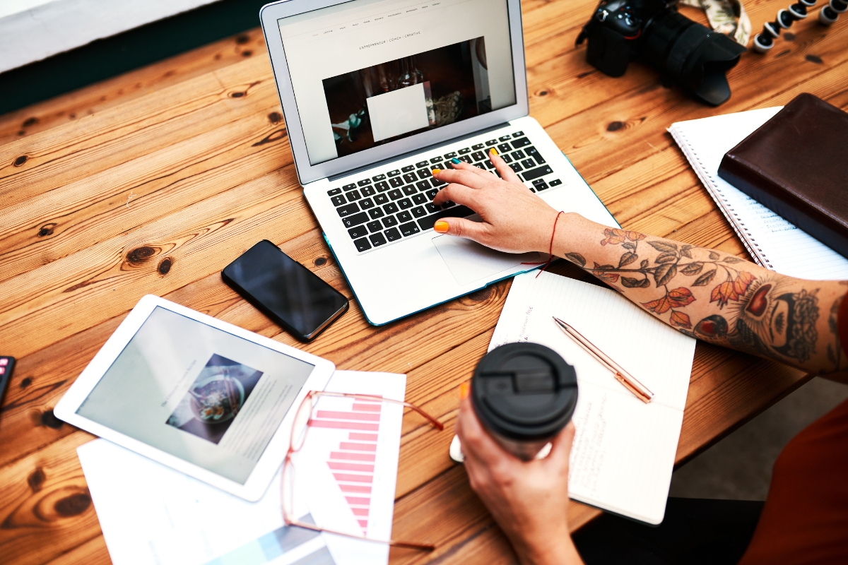 A person guest posting on a laptop at a wooden table.