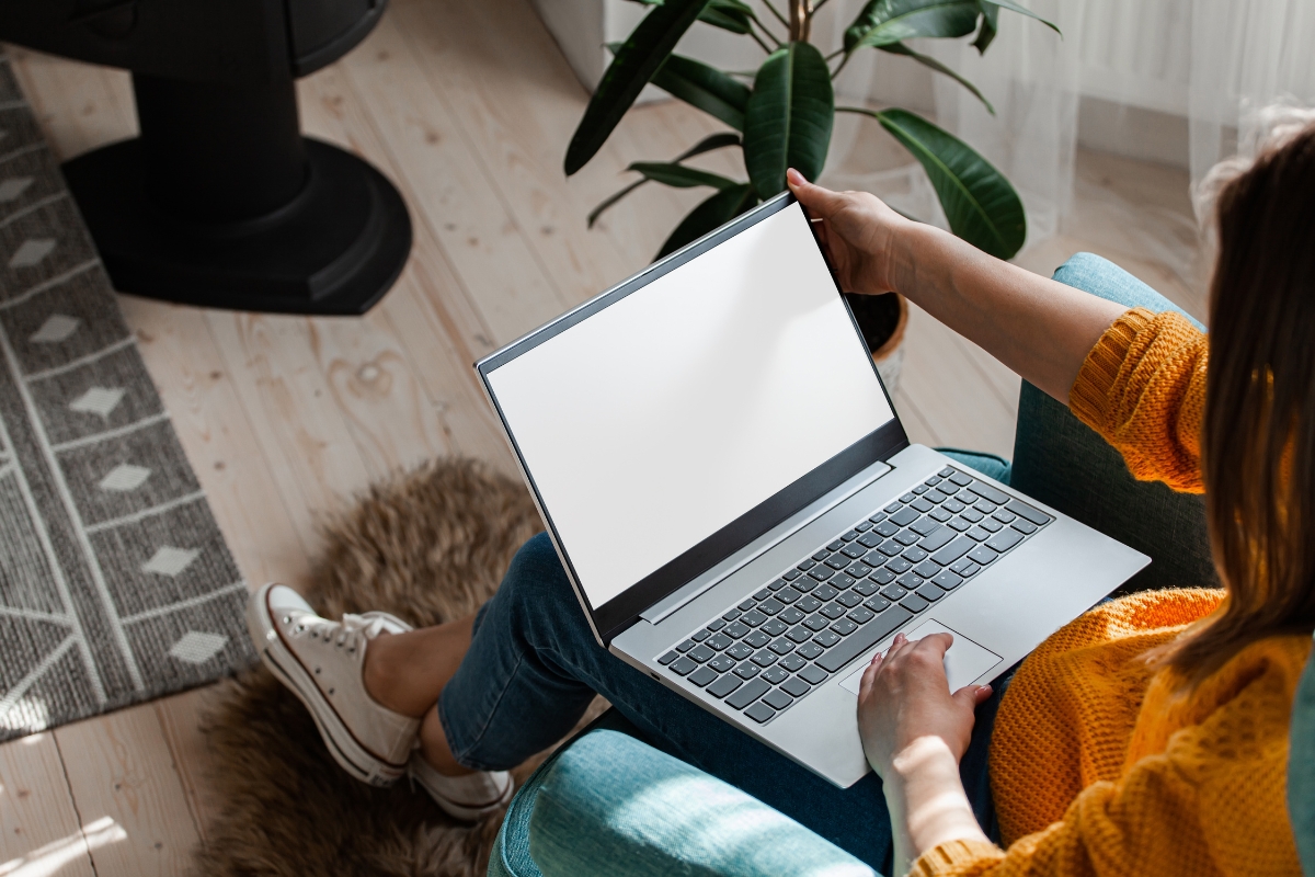 A woman sitting in a chair with a laptop on her lap is working on guest posting.