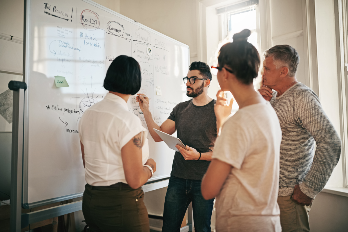 A group of people hiring a content marketing agency standing around a whiteboard.