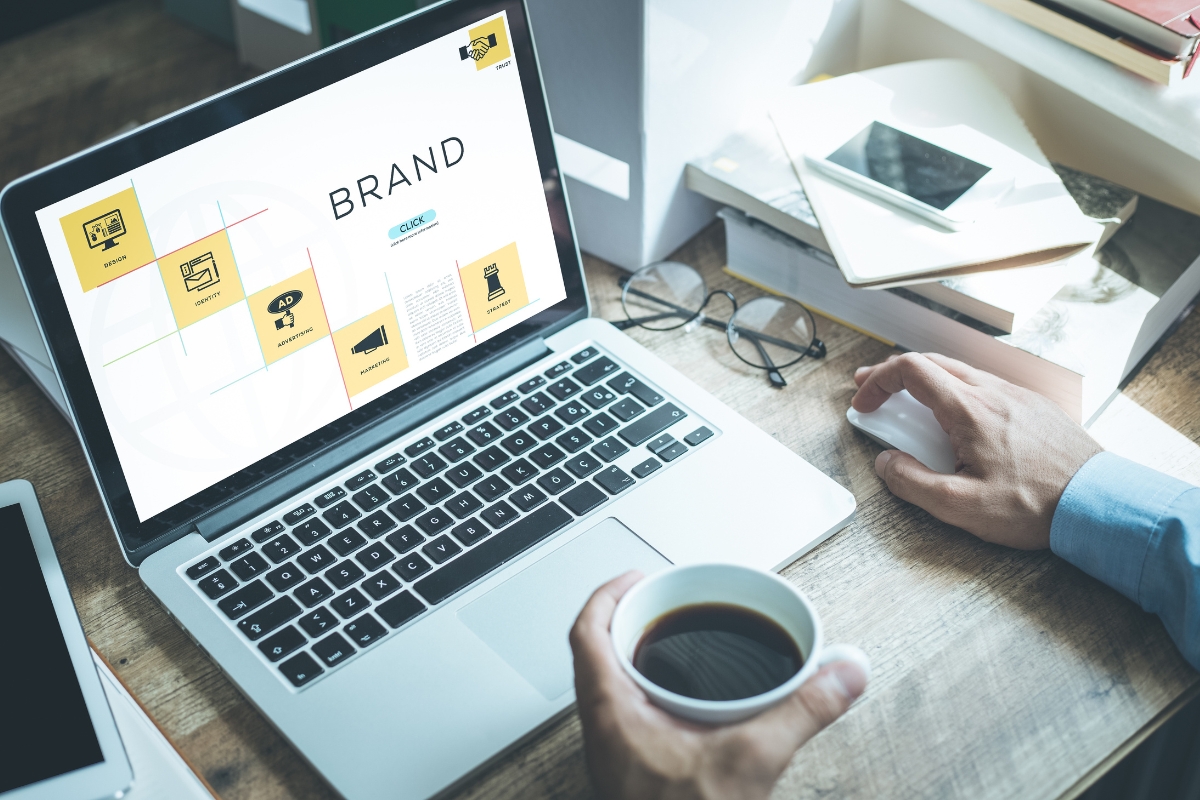 A man working on a laptop with the word "brand" on the screen, helping increase brand awareness.