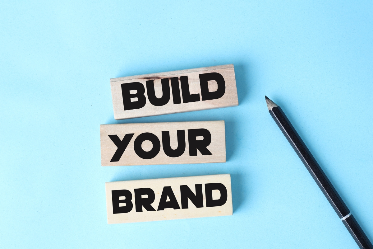 Increase brand awareness by creating a logo with wooden blocks and a pen on a blue background.