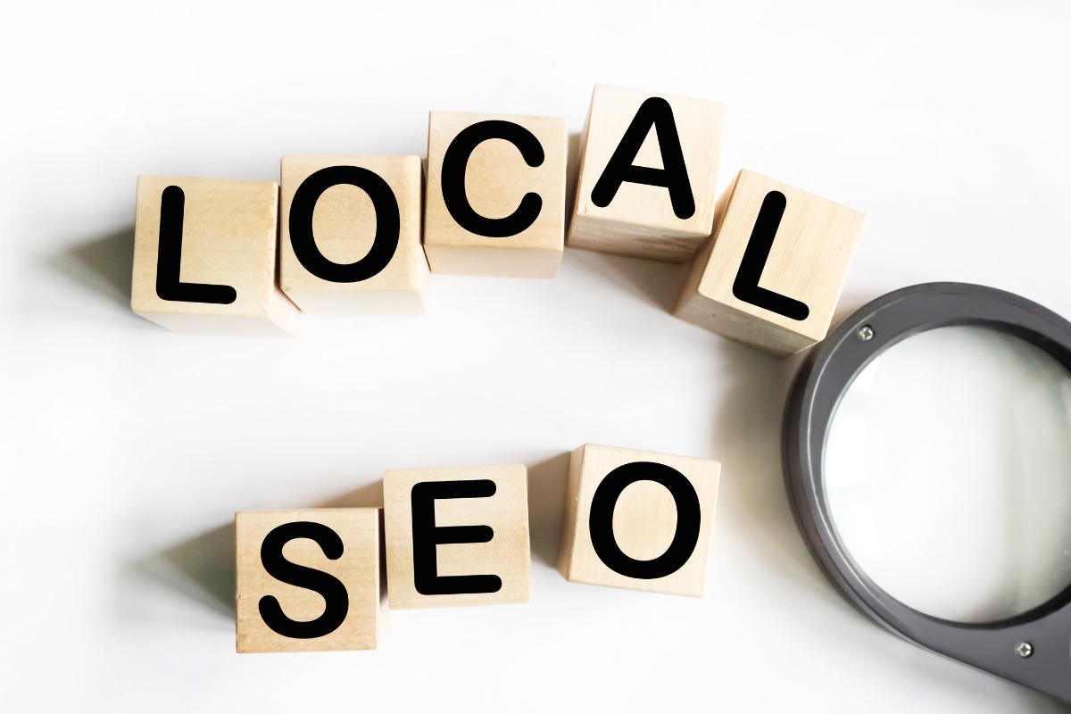 A wooden cubes with black letters next to a magnifying glass for local SEO.