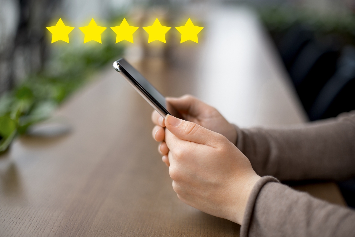 A person using a cell phone with five stars on it, researching local SEO citations.