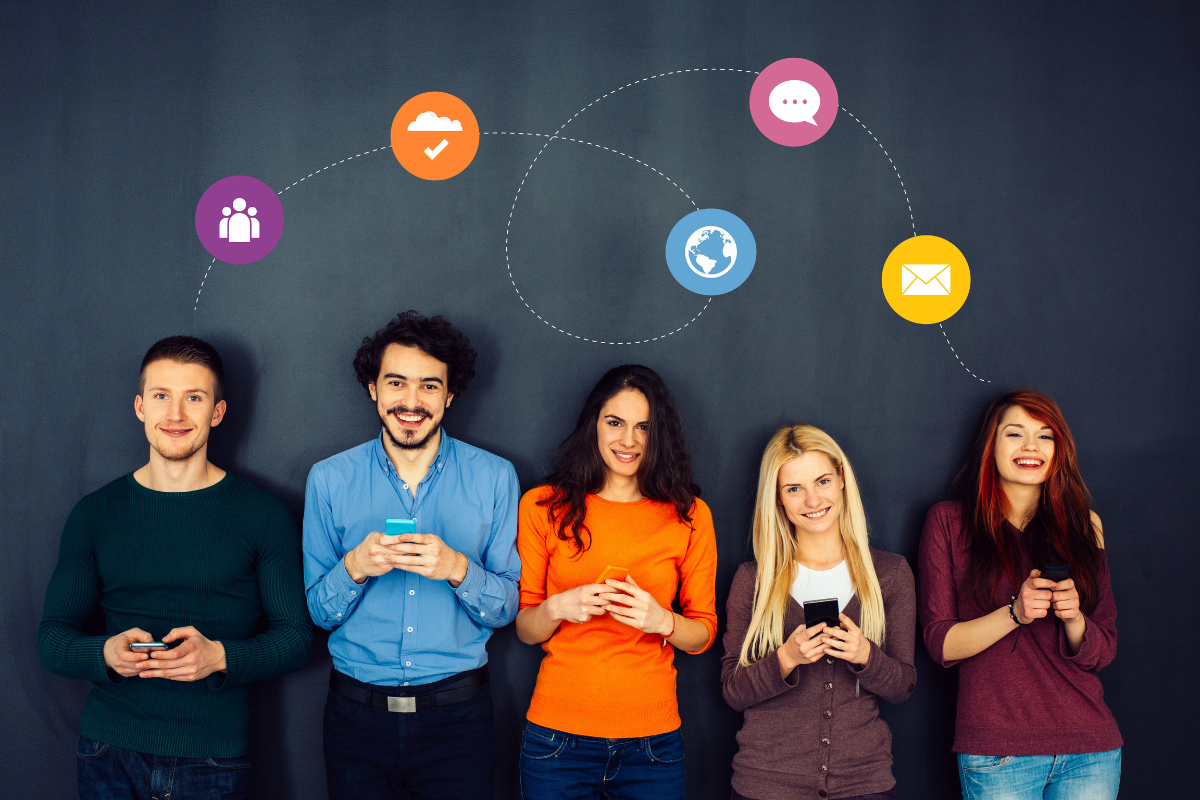 A group of people standing in front of a wall while holding their mobile phones.