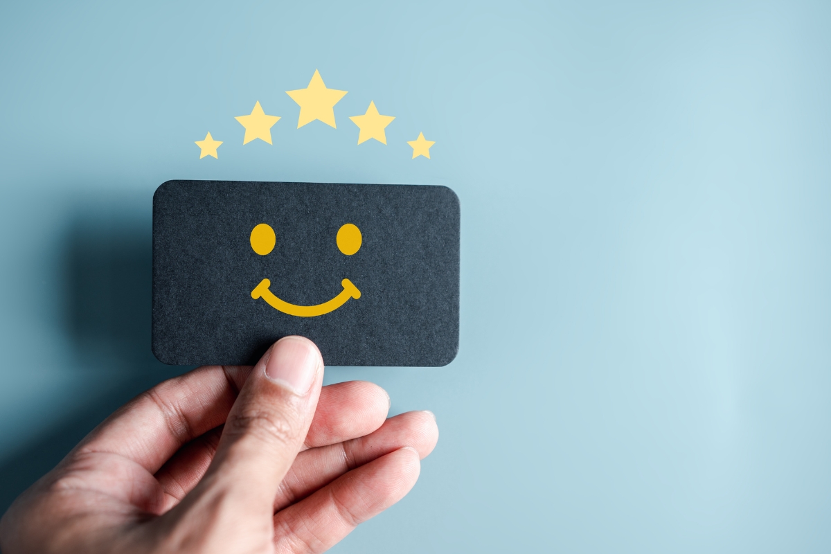 A person holding a card with a smiley face and stars on it, despite negative reviews.