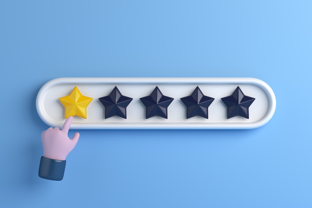 A hand points at a five star rating scale on a blue background, potentially signaling negative reviews.