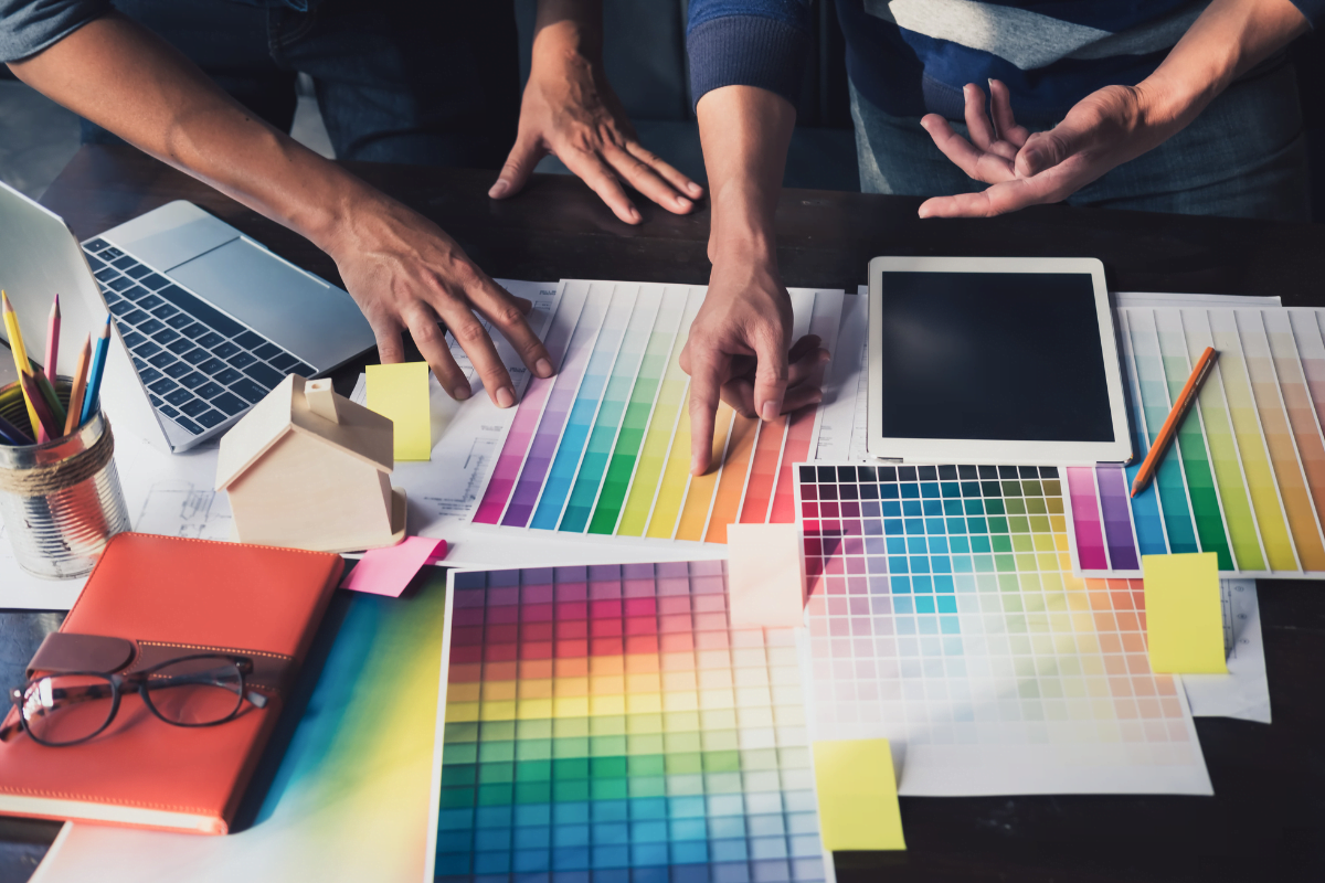 A group of people working on a desk with color swatches, examining the psychology of color in marketing.