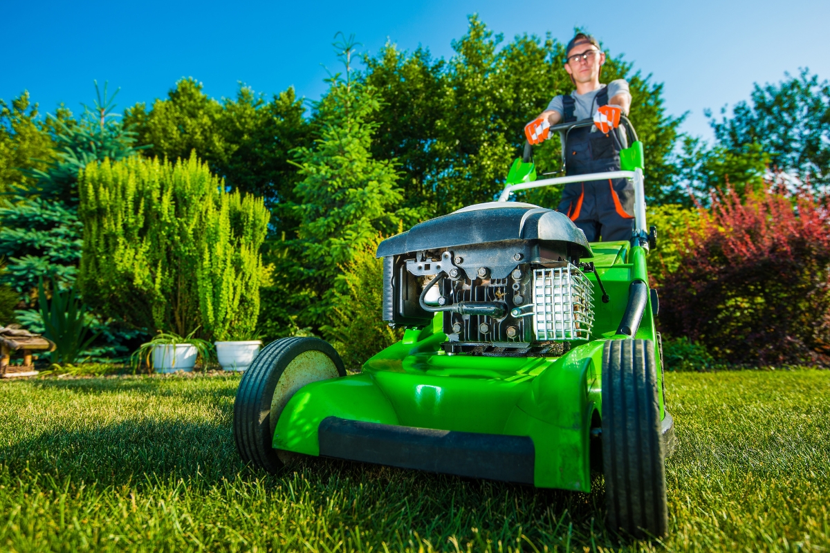 A man with a green lawn mower implements SEO for landscaping.