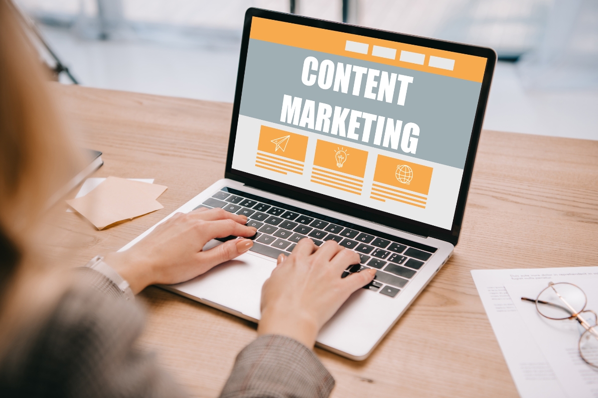 A woman working on a laptop with the words "content marketing" displayed.