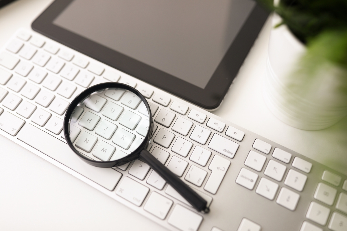 A magnifying glass sits on top of a keyboard, enhancing SEO performance.