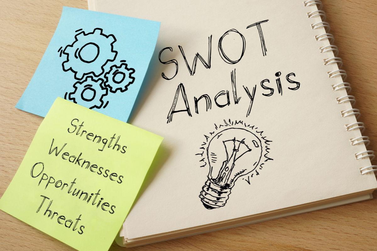 A notebook with a drawing of gears and light bulb on it, inspired by a SWOT analysis guide.