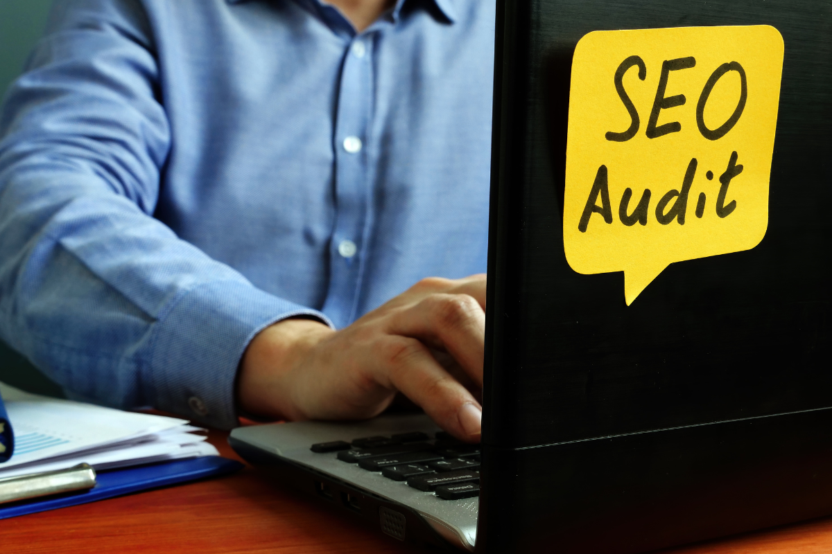 A man using a laptop with the word SEO audit on it.