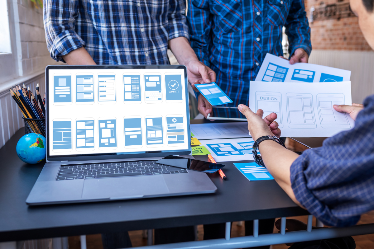 A group of people viewing a laptop screen to understand what is a website.