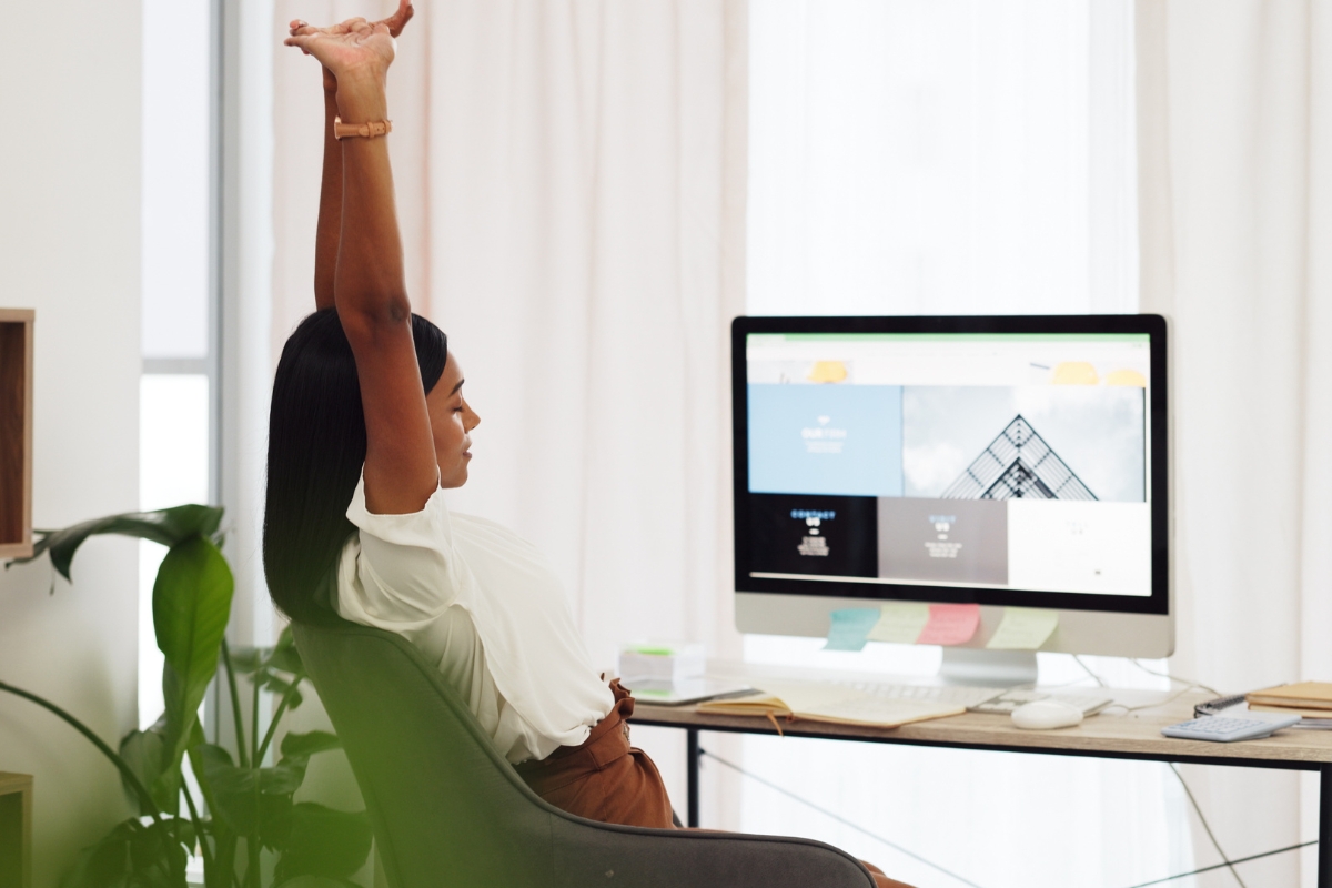 A woman raising her arms in front of the computer screen, celebrating a WordPress challenge completed.