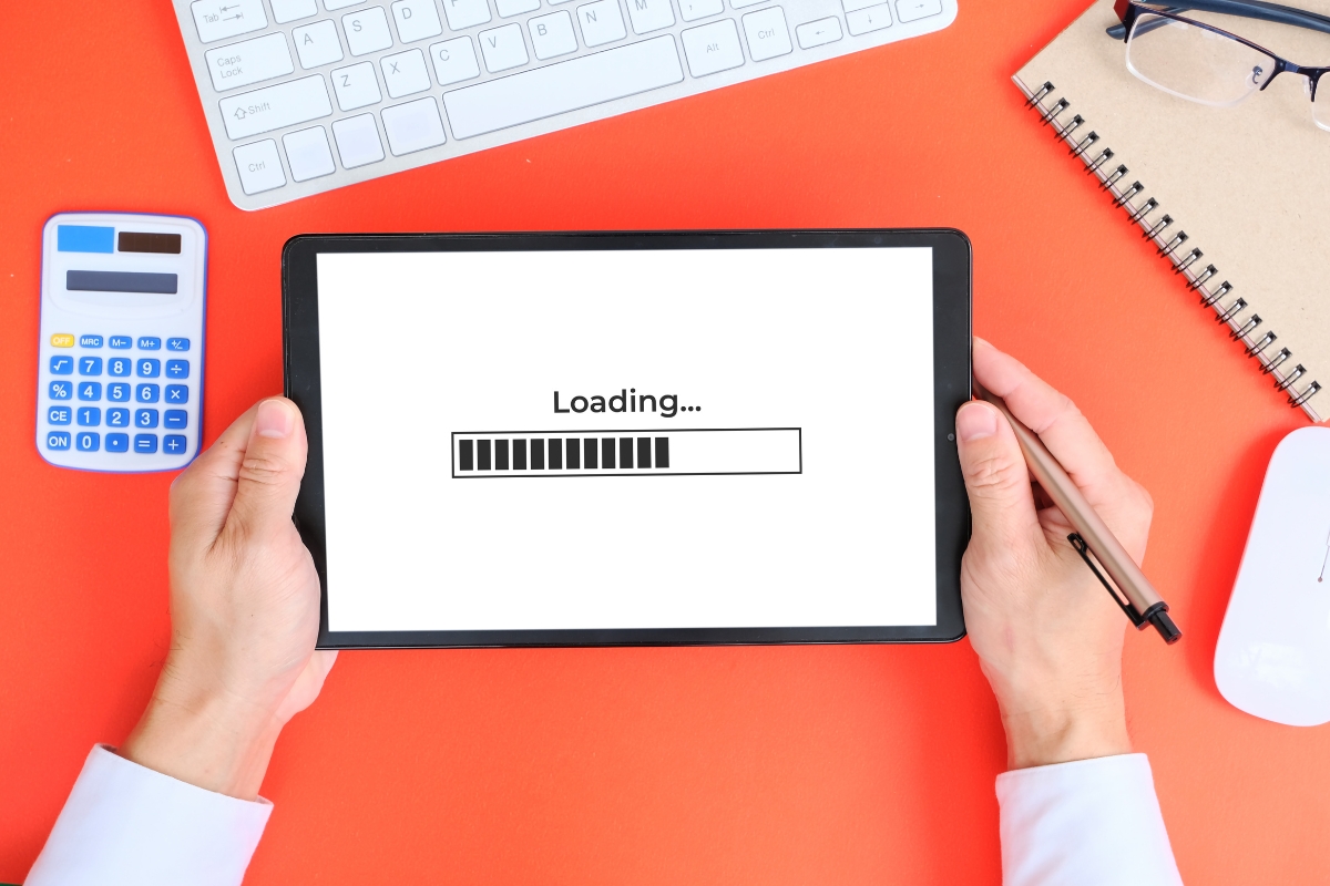 A person facing wordpress challenges holds a tablet with the word loading on it.