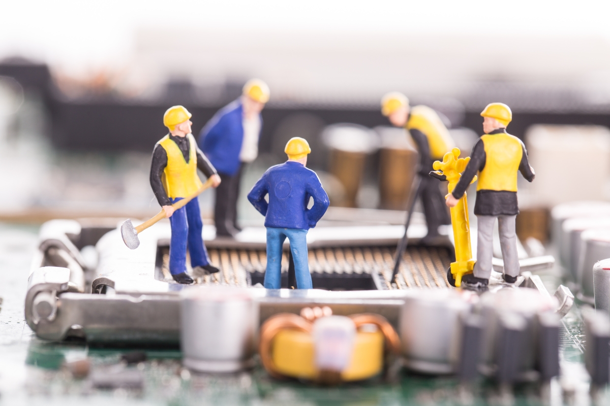 Tiny construction worker figurines on a motherboard.