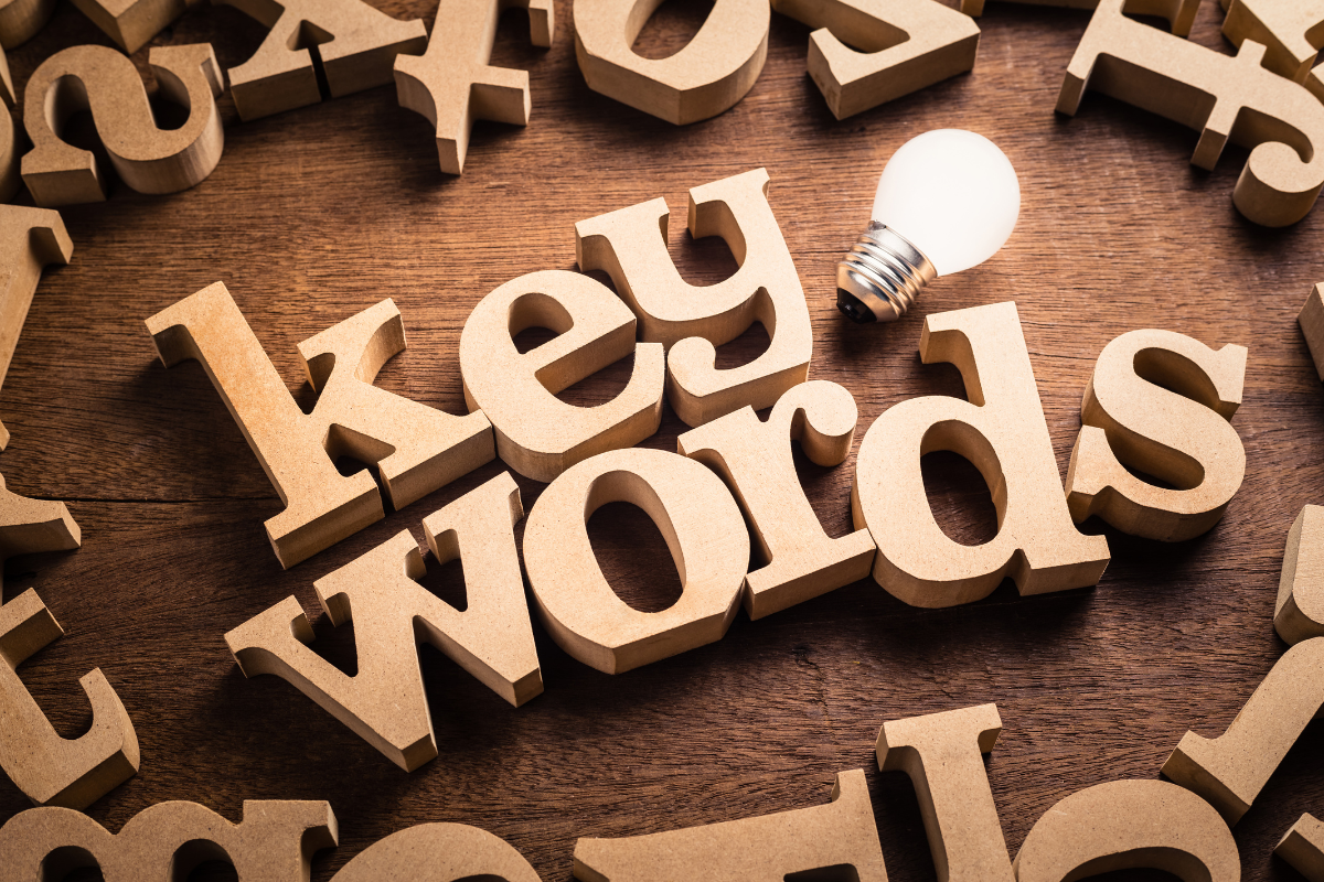 A light bulb surrounded by wooden letters with the word "keywords" for how to choose the right keywords.