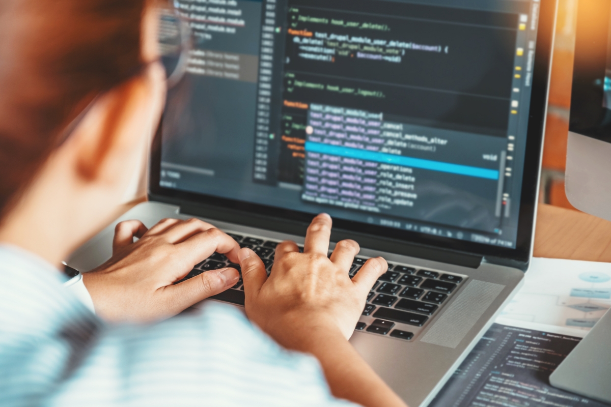 A woman is working on a laptop with code minification on it.