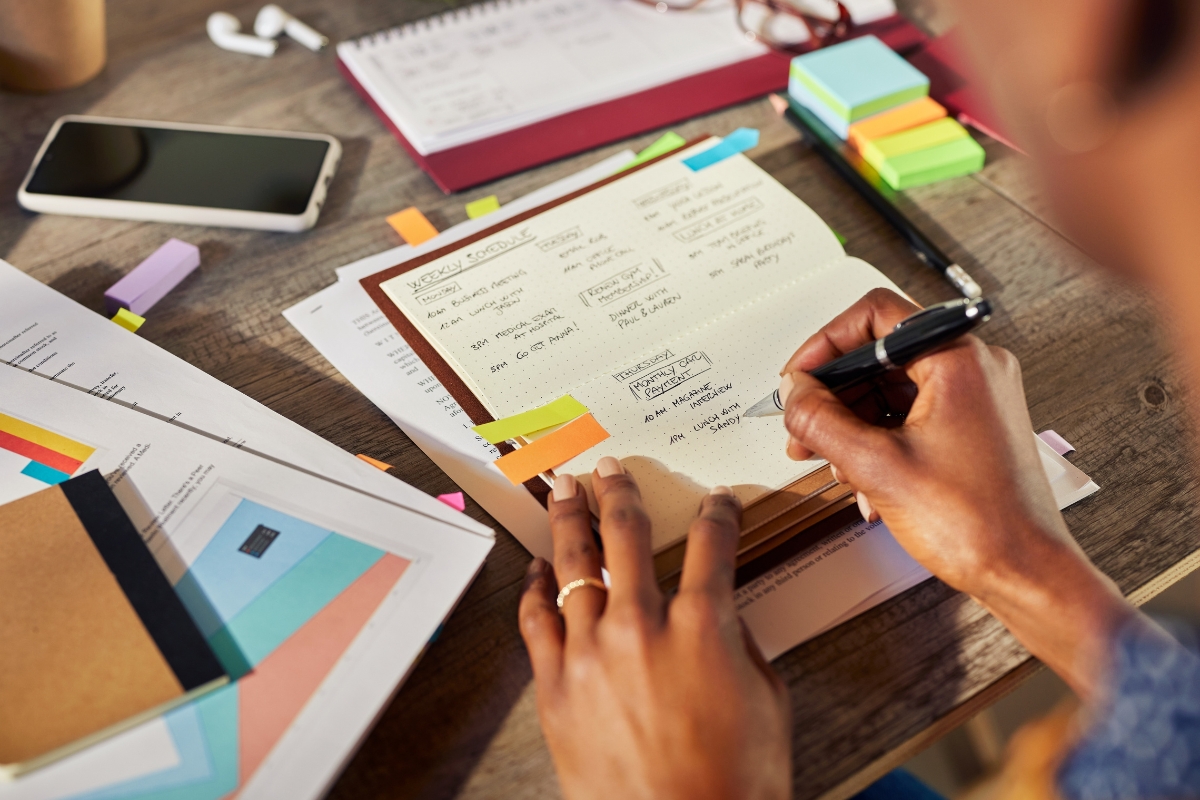 A person organizing a content calendar with sticky notes and charts on a wooden desk.