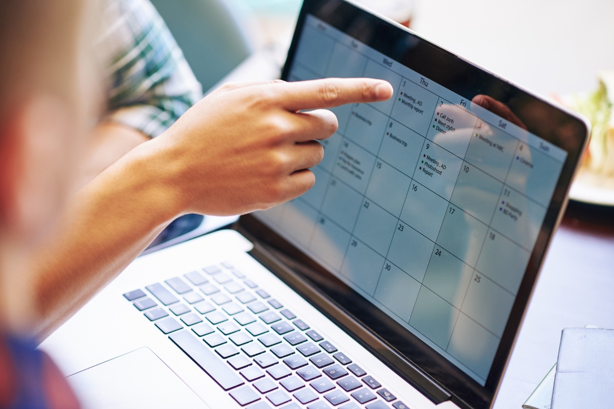 Person pointing at a content calendar on a laptop screen.