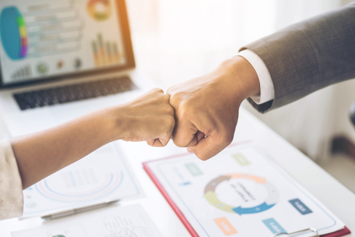 Two business people shaking hands in front of a desk, finalizing a content syndication deal.