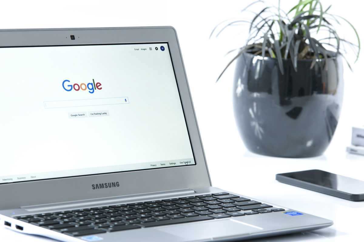 A laptop open to the Google Guaranteed Local Services homepage beside a potted plant on a white desk.