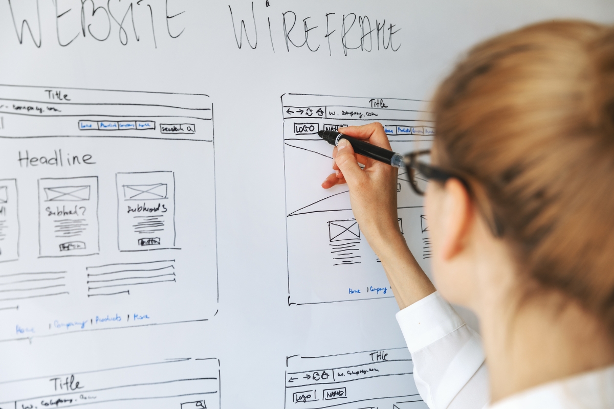 A person illustrating how to create website wireframes on a whiteboard.