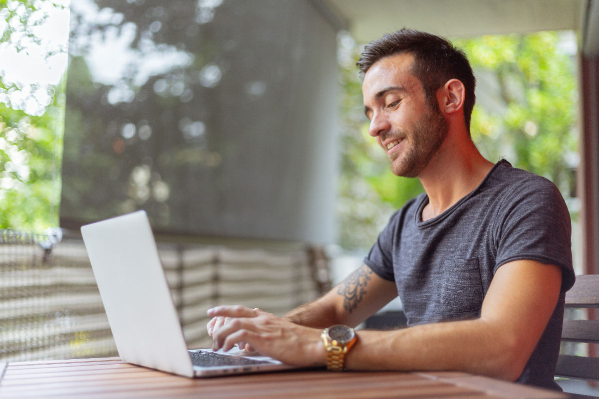 A man sitting at a table using a laptop.