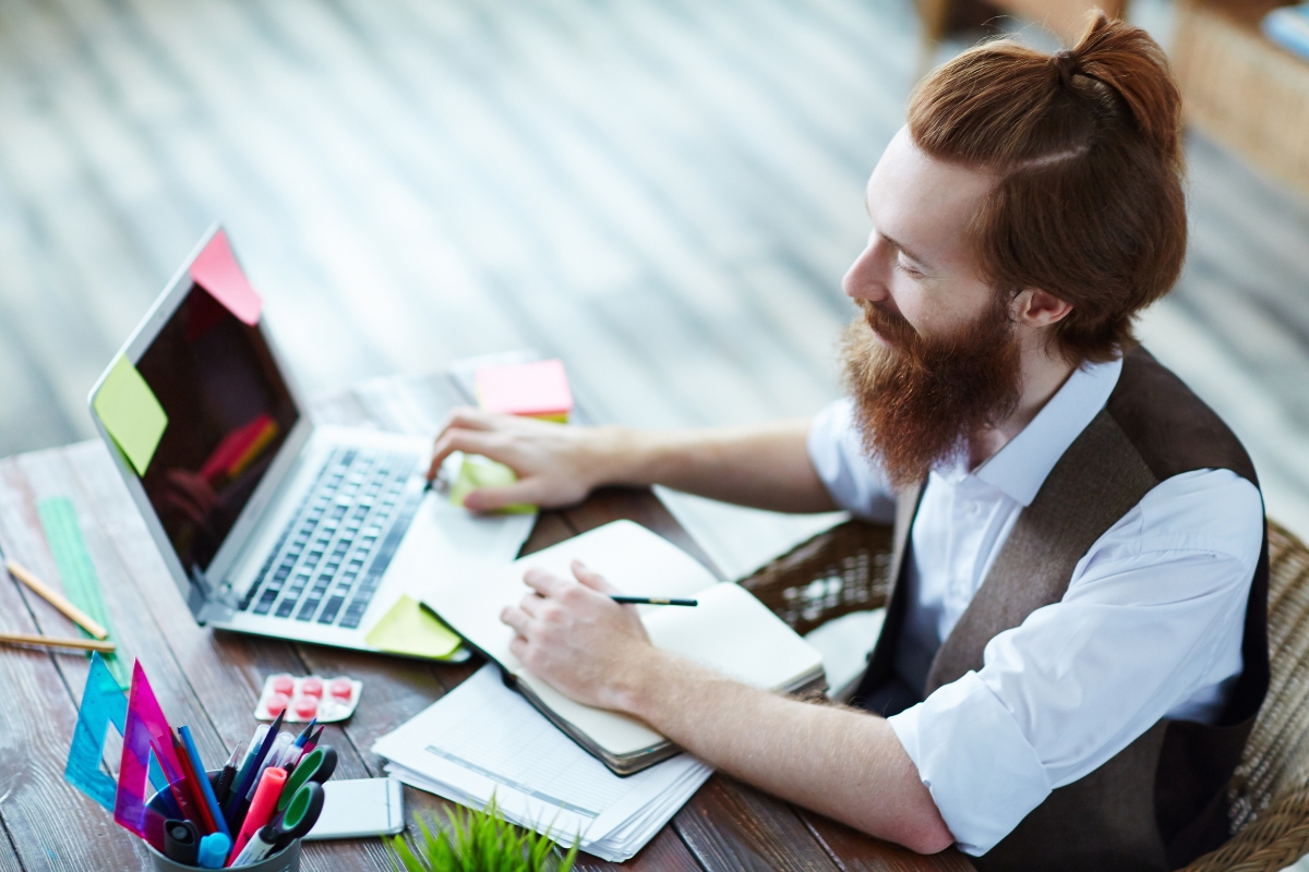 A man with a beard sitting at a desk with a laptop, working on Mailchimp.