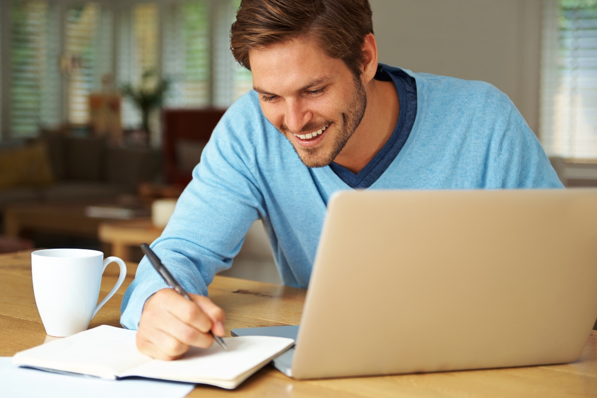 A man sitting at a table with a laptop and a cup of coffee, focusing on SEO for Medium strategy.