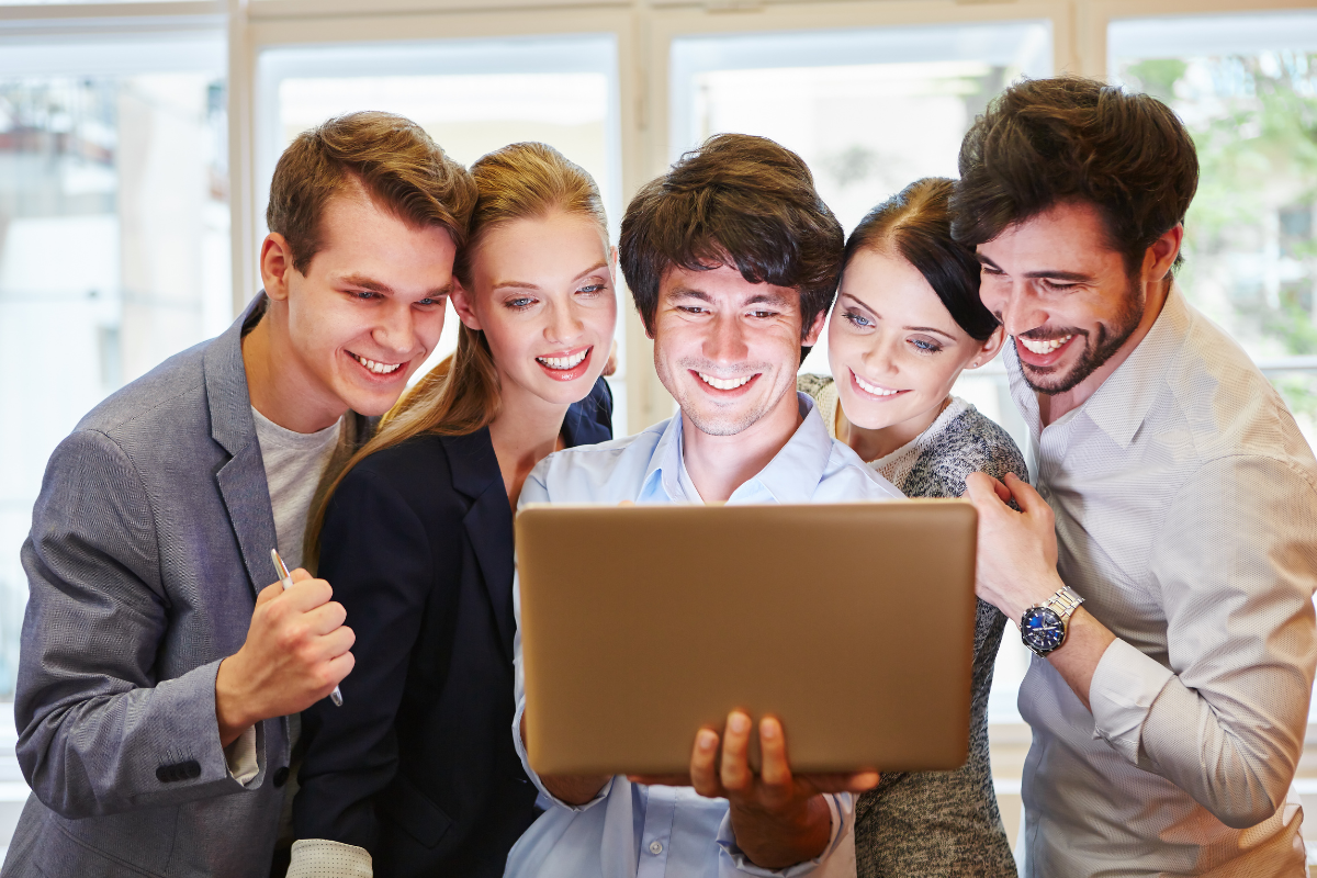 A group of people looking at a laptop celebrating their website success.