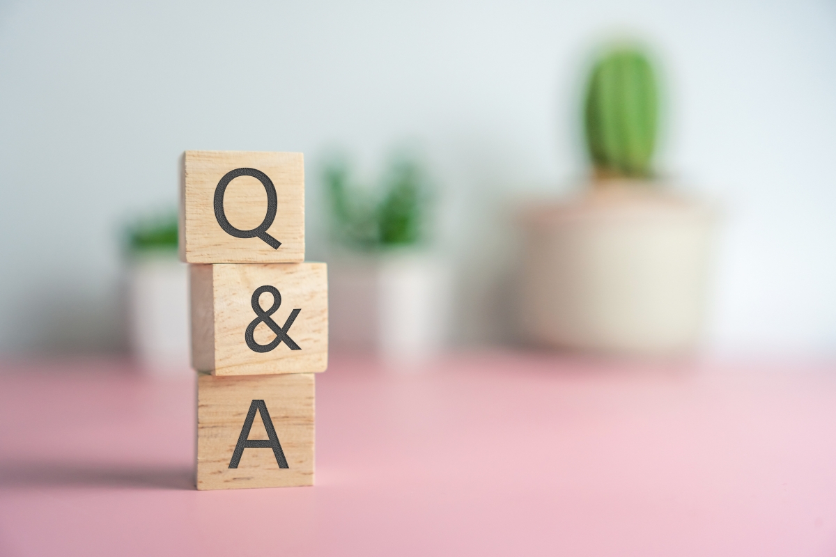 Wooden blocks with the letters "q&a" stacked on a pink surface, designed for Reddit marketing, with a blurred cactus in the background.