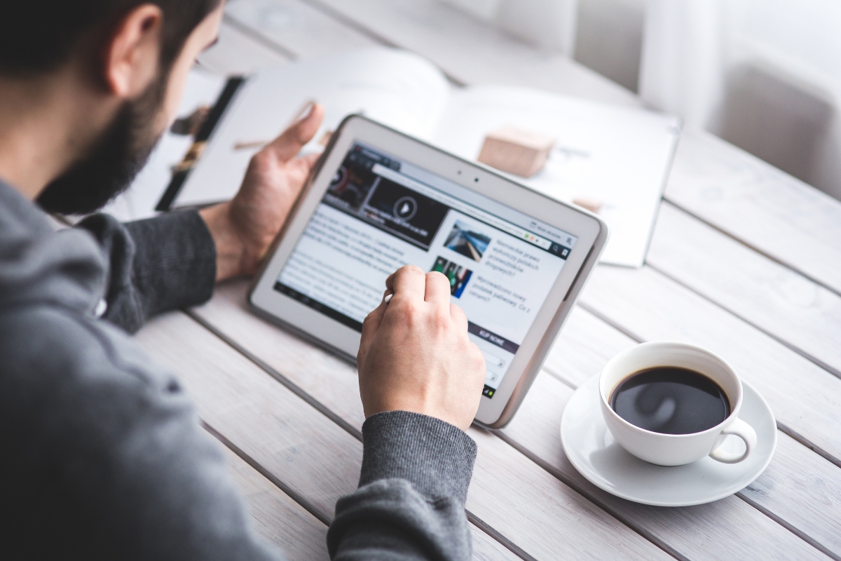 A person browsing Reddit marketing strategies on a tablet next to a cup of coffee on a wooden desk.