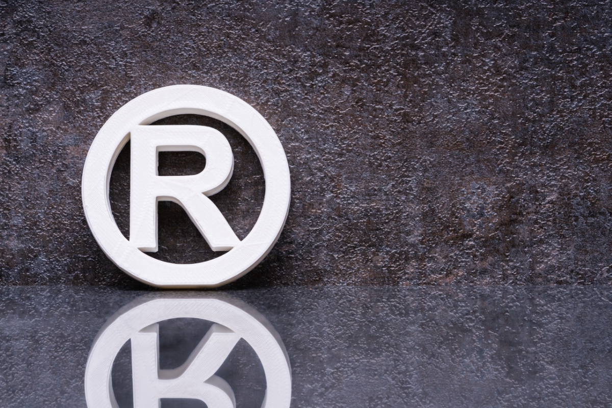 White registered trademark symbols on a reflective surface with a dark textured background.