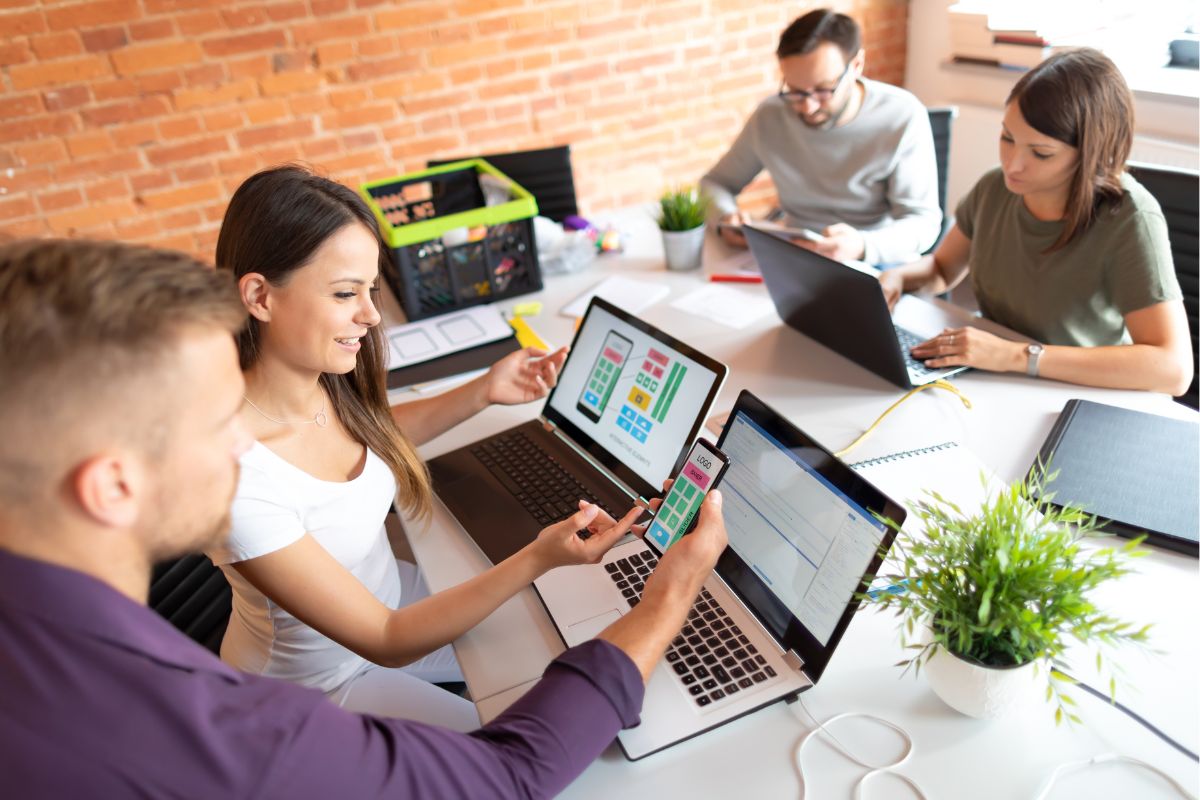 Team of professionals discussing a mobile application development project with SEO techniques in a modern office setting.