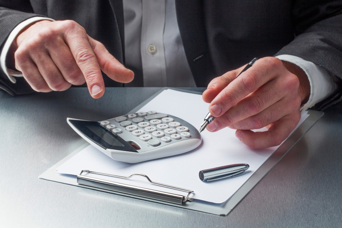 Businessperson using a calculator and taking notes on a pad for service-based business marketing.