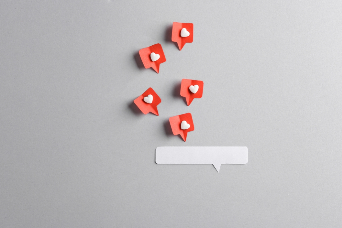 Red heart icons rising from a speech bubble on a gray background, symbolizing growing social media interaction for service based business marketing.