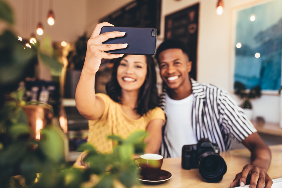 Two people engaging in social media by taking a selfie together in a cozy café setting.