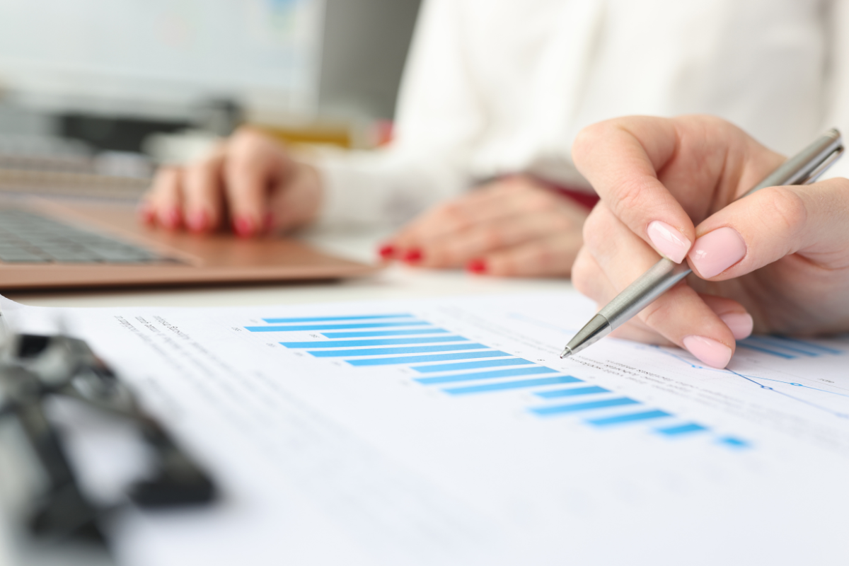 A woman is reviewing data on a piece of paper with a pen.